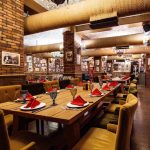 restaurant-hall-with-red-brick-walls-wooden-tables-pipes-ceiling_140725-8504